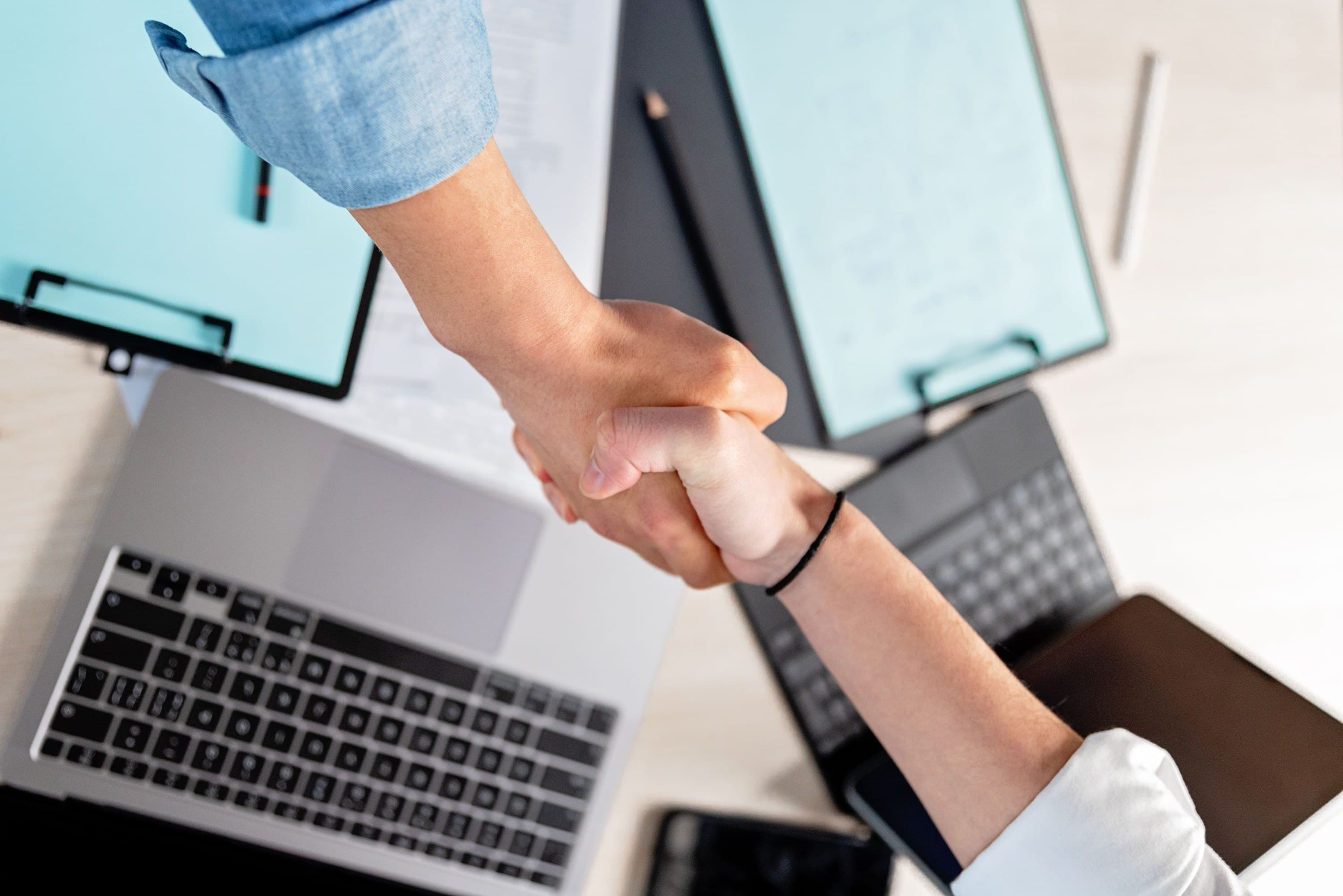 Deux personnes se serrent la main au-dessus d'un bureau